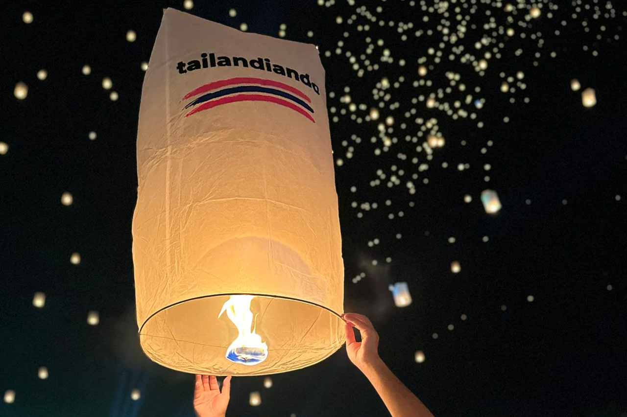 A logo da Tailandiando brilhando no céu durante o Festival das Lanternas em Chiang Mai.